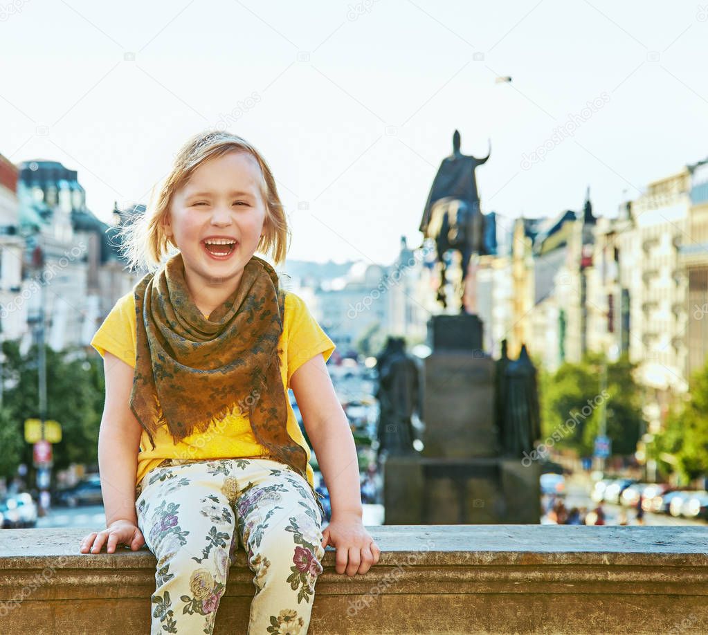 smiling child on Wenceslas Square in Prague sitting on parapet