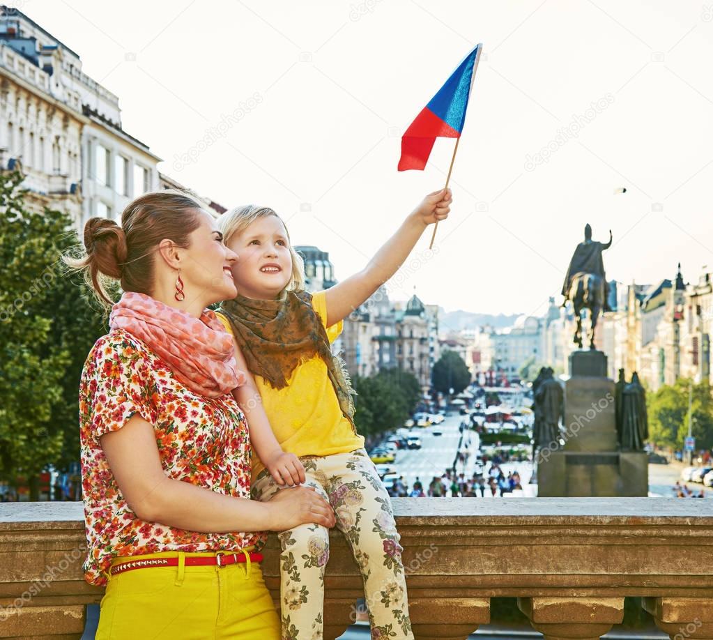 happy mother and daughter tourists in Prague rising flag