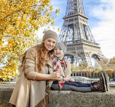 Paris'te parapetin üzerinde oturan Anne ve kızı gezginler