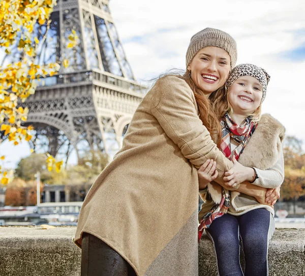 mother and child tourists embracing on embankment in Paris