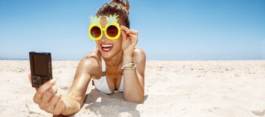 Kumlu plajda selfie alarak ananas gözlük gülümseyen kadın