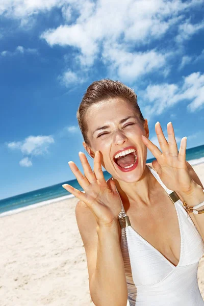 Mujer gritando a través de megáfono en forma de manos en la playa de arena —  Fotos de Stock