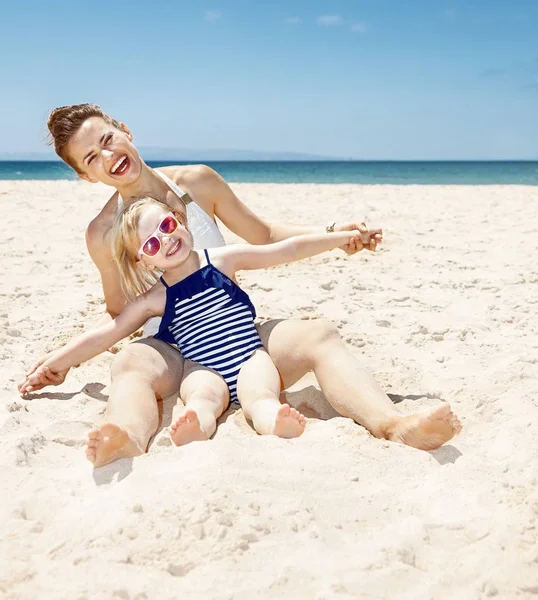 Feliz madre e hijo en trajes de baño en la playa de arena jugando — Foto de Stock