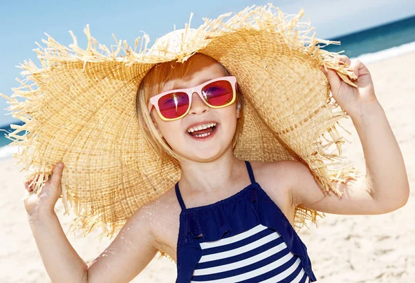 Smiling girl in swimsuit and big straw hat on a white beach — Stock Photo, Image