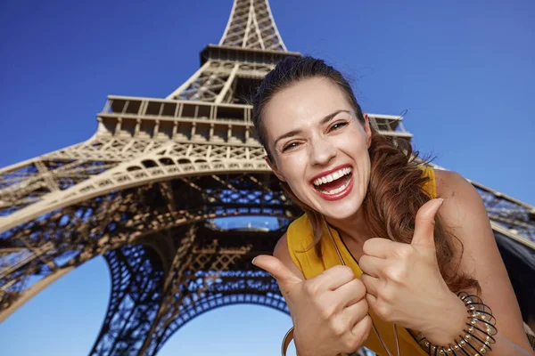 Mosolygó fiatal nő mutatja remek-előtt a Eiffel-torony — Stock Fotó