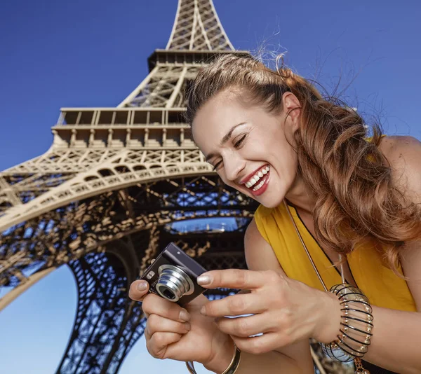 Feliz joven mujer viendo fotos delante de la torre Eiffel —  Fotos de Stock