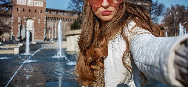 trendy woman near Sforza Castle in Milan, Italy taking selfie