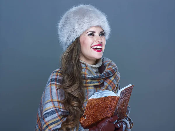 Sonriente mujer aislado en frío azul con libro buscando en copia sp —  Fotos de Stock