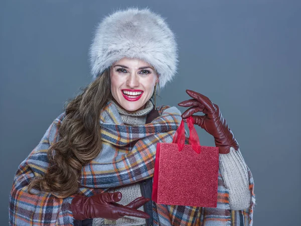 Mujer aislada sobre fondo azul frío mostrando pequeño shoppin rojo —  Fotos de Stock