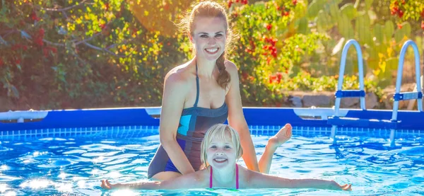 Mãe ativa feliz ensinando filha a nadar na piscina — Fotografia de Stock