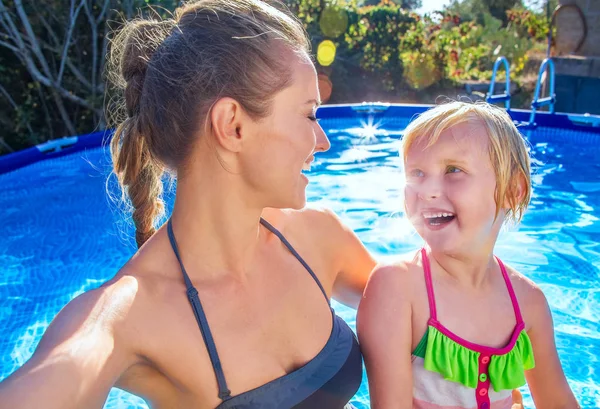 Smilende sund mor og barn i swimmingpool tager selfie - Stock-foto