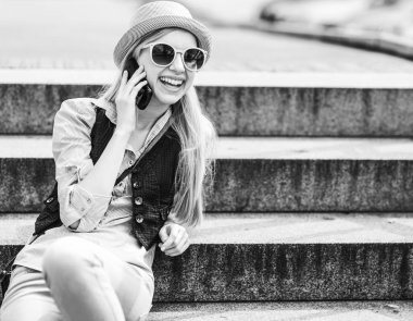 Merdivenlerin üzerinde otururken cep telefonu konuşurken mutlu hippi kız