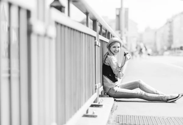 Joven hipster sentado en la calle de la ciudad con cámara fotográfica retro — Foto de Stock