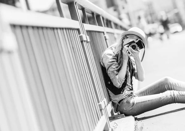 Hipster menina fazendo foto com câmera retro enquanto sentado em cit — Fotografia de Stock