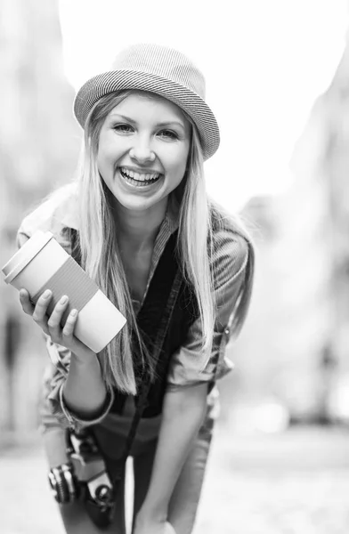 Sorrindo hipster menina com xícara de bebida quente na rua da cidade — Fotografia de Stock