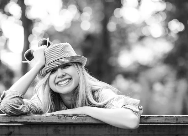 Sorrindo hipster menina sentada no banco no parque — Fotografia de Stock