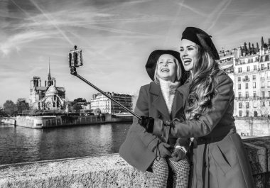 Paris'te parlak. Paris, Fransa için dolgu üzerinde kırmızı kat olarak modern anne ve çocuk turist selfie stick kullanarak selfie alarak