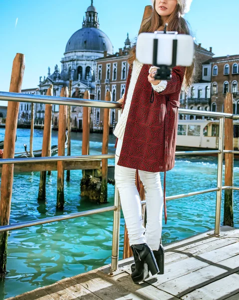 Женщина на набережной в Венеции делает селфи с помощью селфи-палки — стоковое фото