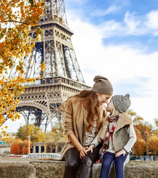 Paris, Fransa'da setin parapetin üzerinde oturan anne ve kızı gezginler gülümseyen tam uzunlukta portresi