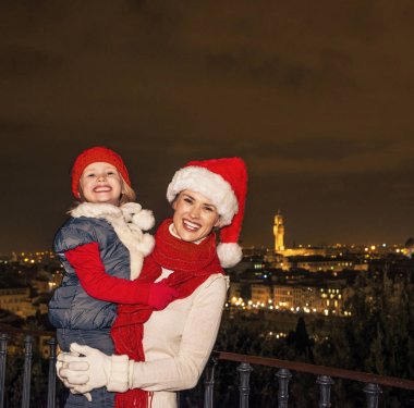 Gezi Floransa'da Noel anda ilham dolu. Neşeli modern anne ve kızı turist Noel şapka Piazzale Michelangelo Floransa, İtalya, portre
