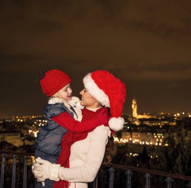 Gezi Floransa'da Noel anda ilham dolu. Modern anne ve çocuk gezginler ile Noel şapka Piazzale Michelangelo, Floransa, İtalya kucaklayan içinde gülümseyen