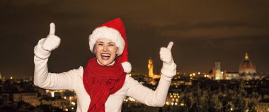 Gezi Floransa'da Noel anda ilham dolu. başparmak gösterilmesini gülümseyen genç kadın Noel şapkalı Floransa, İtalya