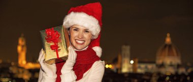 Gezi Floransa'da Noel anda ilham dolu. Piazzale Michelangelo Florence, İtalya gösteren Noel mevcut kutusunda, Noel şapkalı mutlu genç kadın