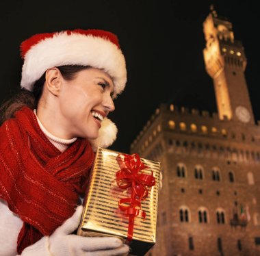 Gezi Floransa'da Noel anda ilham dolu. mutlu modern turist kadın Noel hediyesi kutusuyla mesafe içine bakarak Floransa, İtalya Palazzo Vecchio önünde Noel şapkalı