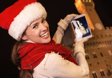 Gezi Floransa'da Noel anda ilham dolu. tablet Pc ile fotoğraf çekme gülümseyen genç kadın Noel şapkalı Floransa, İtalya