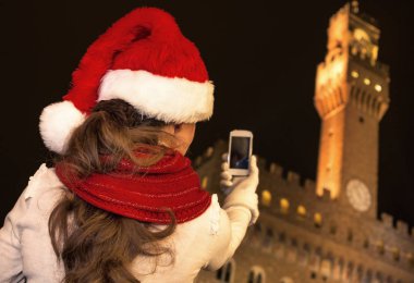 Gezi Floransa'da Noel anda ilham dolu. Floransa, İtalya alarak fotoğraf cep telefonu ile Noel şapka Palazzo Vecchio önünde modern turist kadın