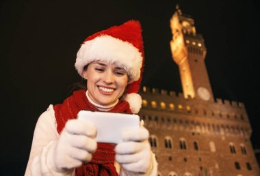 Gezi Floransa'da Noel anda ilham dolu. Noel şapka Palazzo Vecchio Floransa, İtalya kamerada fotoğraf görüntüleme karşı mutlu genç kadın portresi