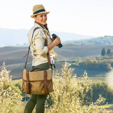 Tuscany büyülü manzarasını keşfetmek. gülümseyen macera kadın hiker Tuscany'de dürbünle hiking şapkalı