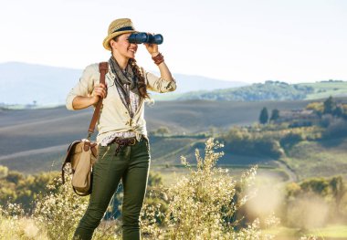 Tuscany büyülü manzarasını keşfetmek. sağlıklı kadın hiker Tuscany çantası ile şapkalı yürüyüş mesafe içine dürbün ile seyir