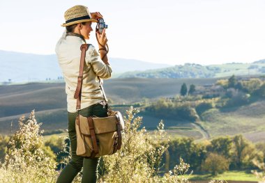 Tuscany büyülü manzarasını keşfetmek. Tuscany alarak fotoğrafta retro fotoğraf makinesi ile hiking şapkalı kadın uzun yürüyüşe çıkan kimse arkasından gördüm