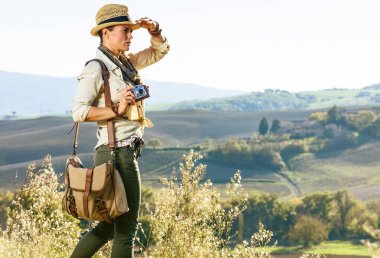 Tuscany büyülü manzarasını keşfetmek. Genç kadın ile mesafe içine vintage fotoğraf kamera ile Tuscany'de hiking çanta şapka uzun yürüyüşe çıkan kimse