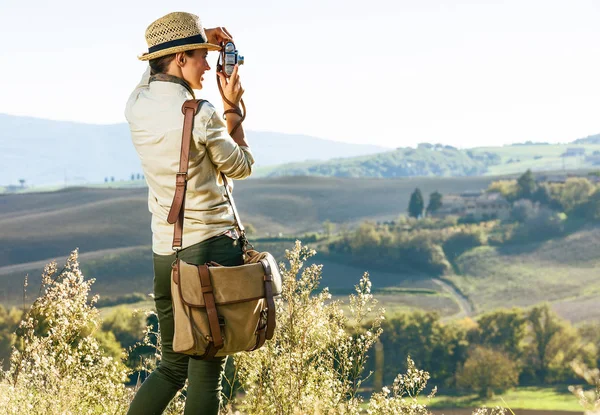 Tuscany büyülü manzarasını keşfetmek. Tuscany alarak fotoğrafta retro fotoğraf makinesi ile hiking şapkalı kadın uzun yürüyüşe çıkan kimse arkasından gördüm