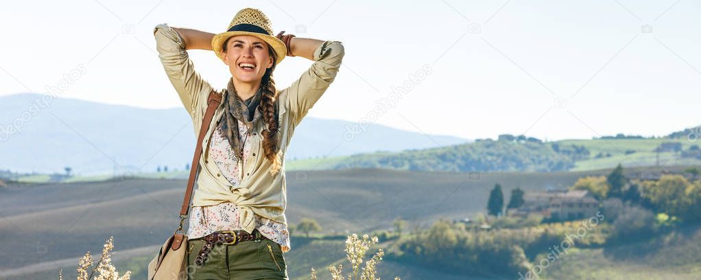 Discovering magical views of Tuscany. relaxed woman hiker in hat with bag enjoying Tuscany view looking into the distance