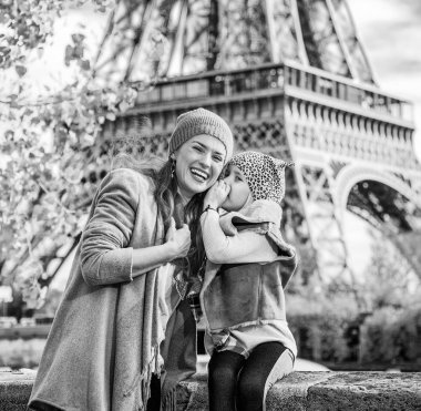 Anne bir şey gülümseyen için setin yakınındaki Eyfel Kulesi Paris, Fransa'da üzerinde fısıldayan kızı portresi