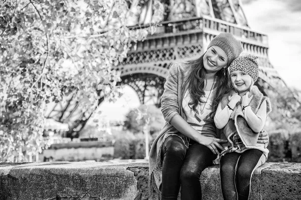 法国巴黎埃菲尔铁塔附近路堤上微笑的母亲和儿童游客的肖像坐在栏杆上 — 图库照片