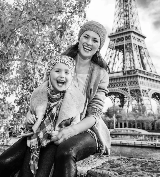 法国巴黎埃菲尔铁塔附近路堤上微笑的母亲和儿童旅行者的肖像坐在栏杆上 — 图库照片