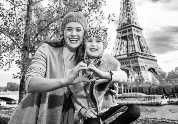 法国巴黎埃菲尔铁塔附近路堤上幸福的母亲和女儿的画像显示心形手 — 图库照片