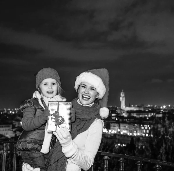 旅行充满灵感在圣诞节的时候在佛罗伦萨 微笑的年轻的母亲和女儿旅客在圣诞帽在佛罗伦萨与圣诞礼物盒的全景视图的肖像 — 图库照片