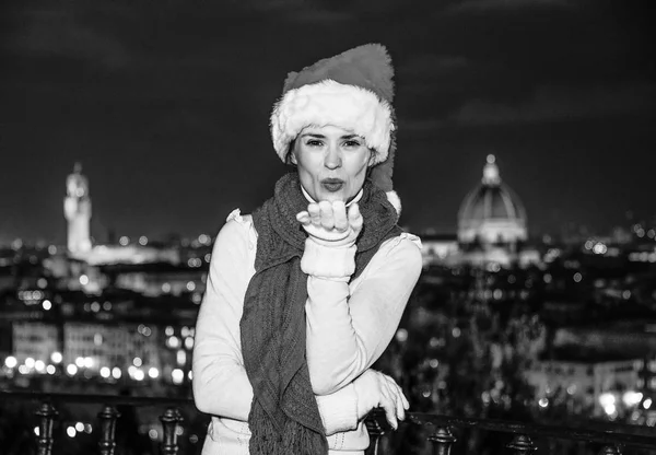 旅行充满灵感在圣诞节的时候在佛罗伦萨 微笑在米开朗基罗广场在意大利佛罗伦萨的吹空气吻着圣诞帽的年轻女子 — 图库照片