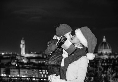 Gezi Floransa'da Noel anda ilham dolu. genç anne ve çocuk gezginler Noel şapka ile Floransa, İtalya öpüşme yılında İtalyan bayrağı ile gülümseyen