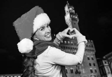 Gezi Floransa'da Noel anda ilham dolu. Noel şapka Palazzo Vecchio Floransa, İtalya kalp gösterilen karşı mutlu genç kadın portresi el şeklinde