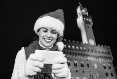 Gezi Floransa'da Noel anda ilham dolu. Noel şapka Palazzo Vecchio Floransa, İtalya kamerada fotoğraf görüntüleme karşı mutlu genç kadın portresi