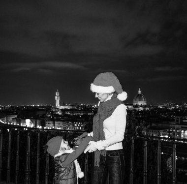 Gezi Floransa'da Noel anda ilham dolu. genç anne ve kızı gezginler Floransa, İtalya oynarken Noel şapka ile gülümseyen