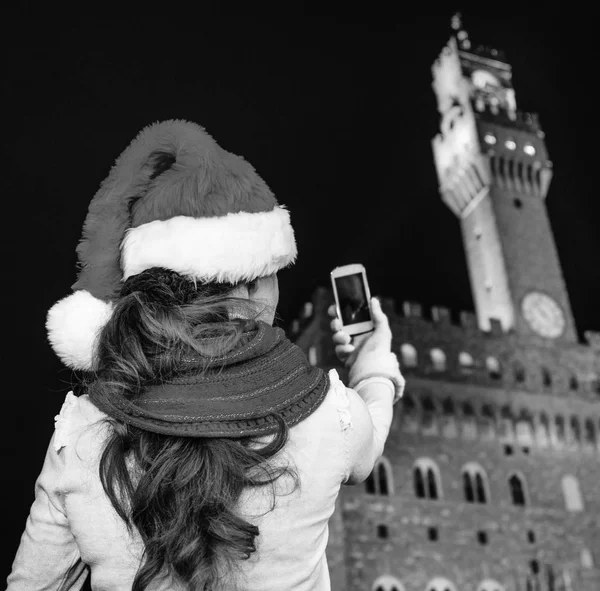 Gezi Floransa'da Noel anda ilham dolu. Floransa, İtalya alarak fotoğraf cep telefonu ile Noel şapka Palazzo Vecchio önünde modern turist kadın