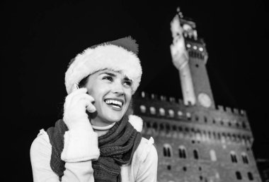 Gezi Floransa'da Noel anda ilham dolu. Gülümseyen genç turist kadın şapkalı Floransa, İtalya bir cep telefonuyla konuşurken Noel Palazzo Vecchio karşı portresi