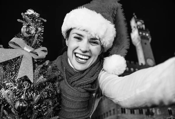 Gezi Floransa'da Noel anda ilham dolu. Floransa, İtalya Palazzo Vecchio önünde Noel şapkasıyla Noel ağacı selfie alarak mutlu modern turist kadın